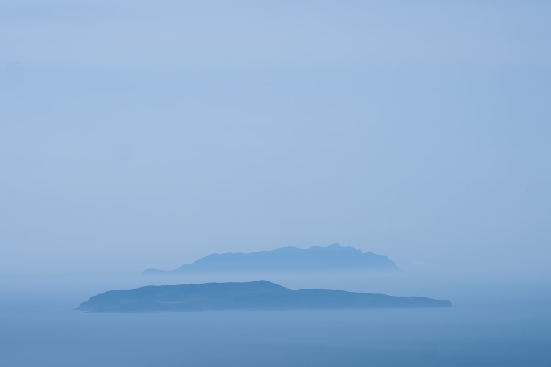 an island in the middle of the ocean on a foggy day